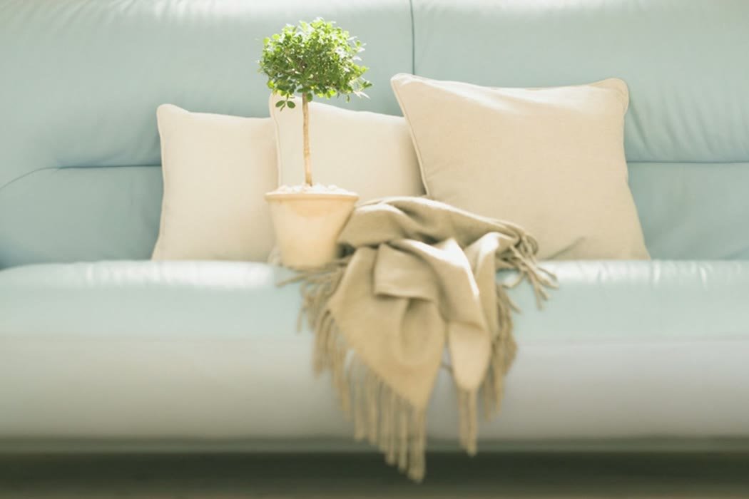 Close view of soft cushions and a woven throw layered on a pale sofa