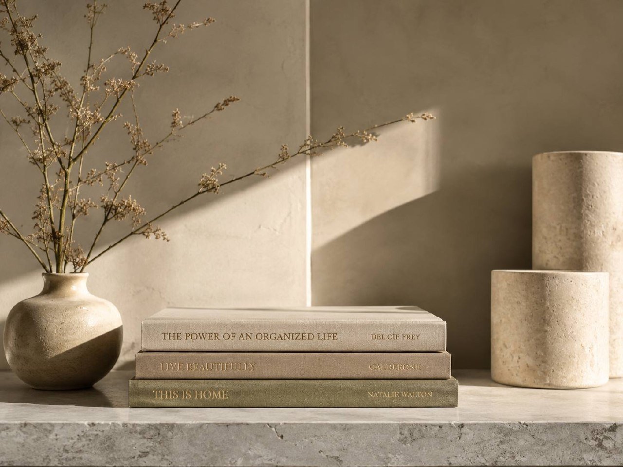 Warmly lit stone console styled with books, a vase, and ceramic vessels