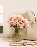 Bouquet of pink roses beside a handbag and gold-toned accessories